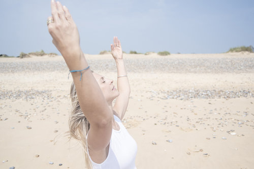 Lady doing Yoga on sandy beach